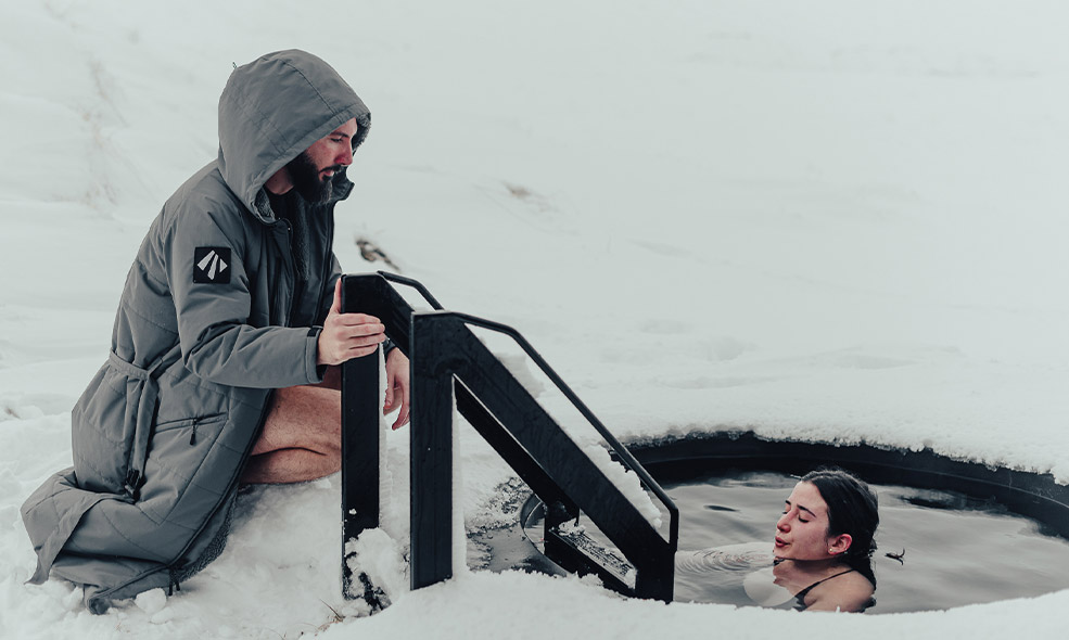 woman does cold plunge up to her neck outside on a snowy day in iceland