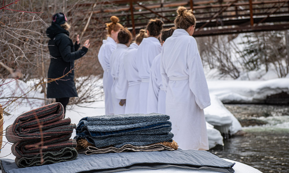 people wear robes as they wait to go in the taylor river for a cold plunge