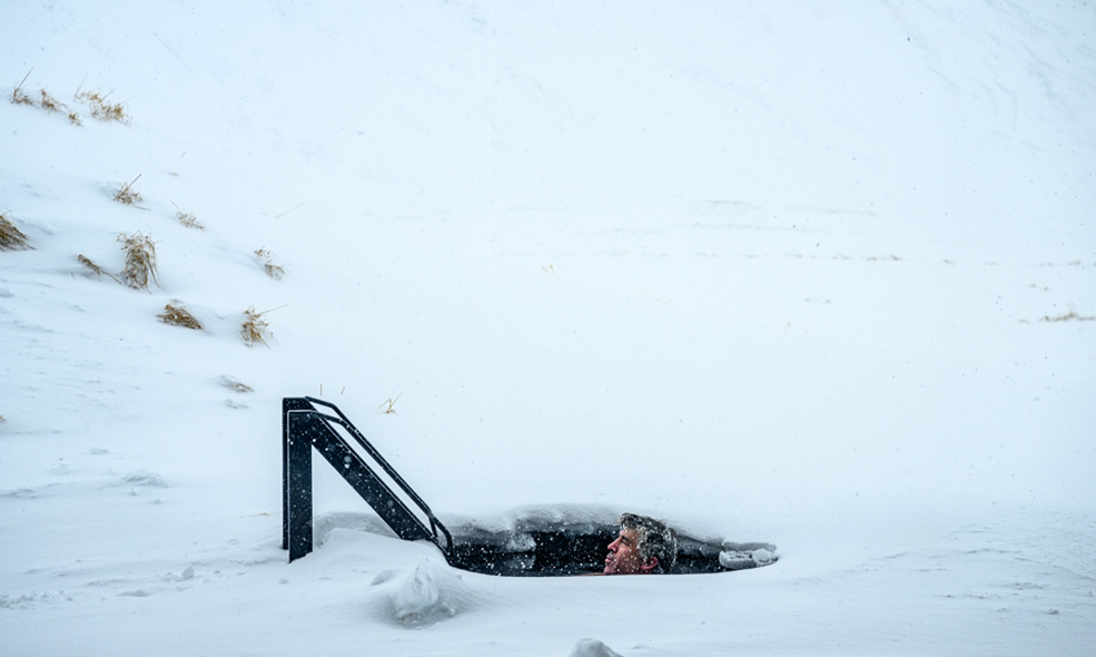 man goes in cold plunge outside on a snowy day in iceland