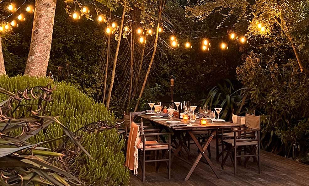 table set for dinner amongst bushes with tea lights for a dinner at eleven cedar lodge, new zealand