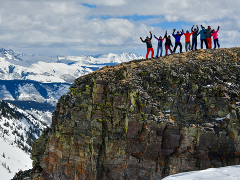 a group of skiers pose in front of a mountain view