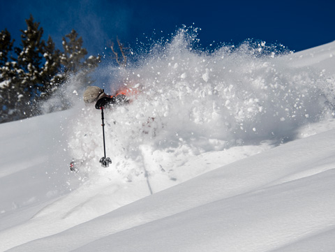 a skier descends through deep powder